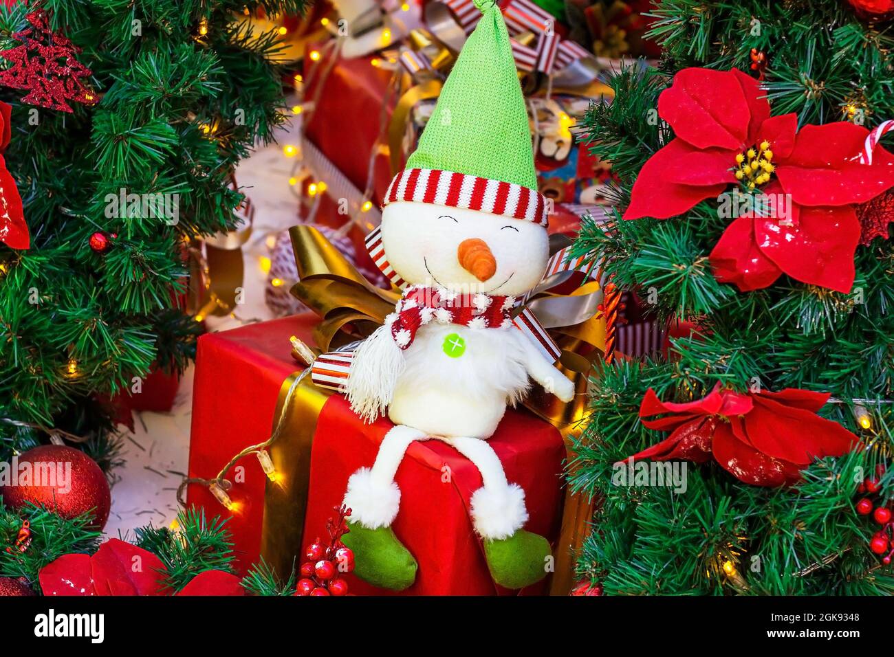 Luminoso pupazzo di neve colorato su scatole regalo vacanza avvolto su albero di abete verde rami sfondo. Natale e Capodanno concetto. Foto Stock