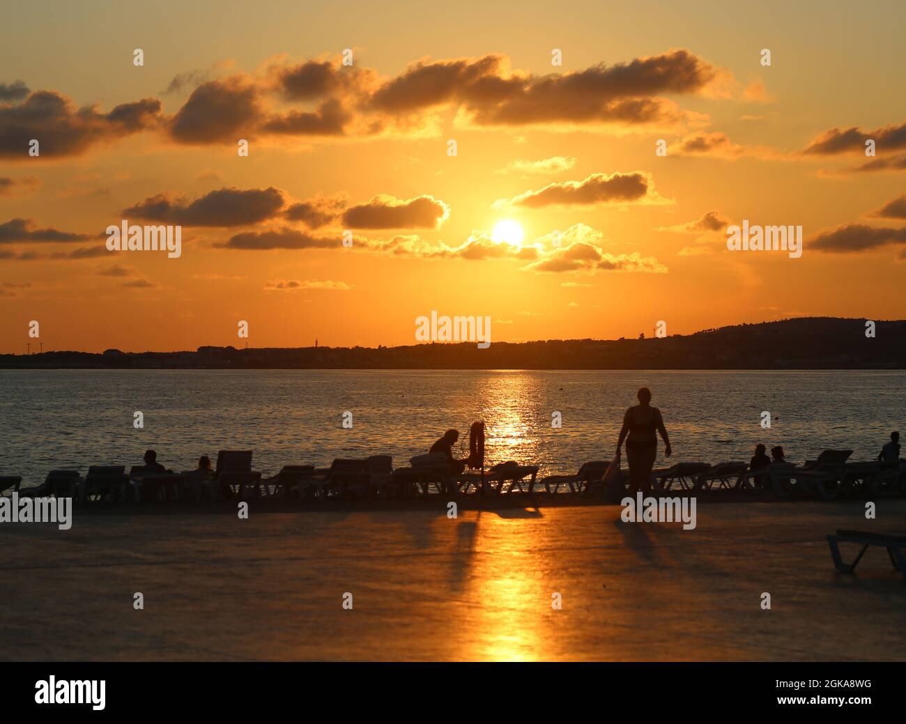Bella foto di un tramonto sul mare con turisti in vacanza sulla spiaggia Foto Stock