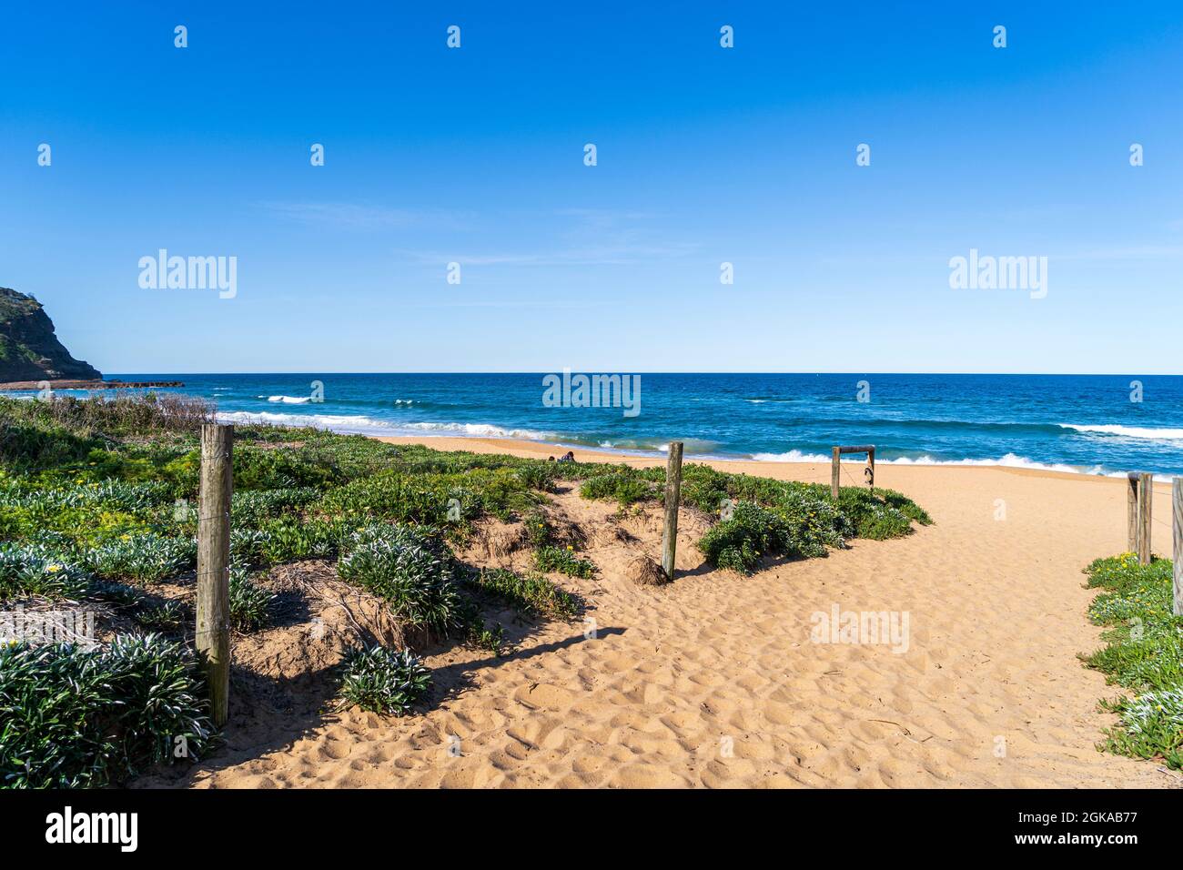 Pista di sabbia alla spiaggia con pali di legno e l'oceano Foto Stock