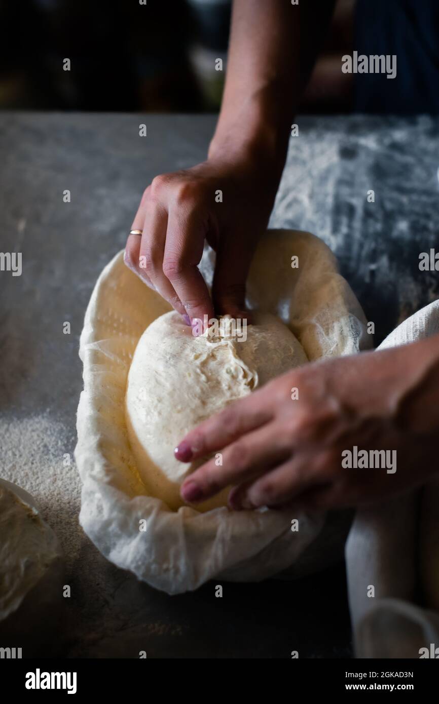 Donna panettiere forma il pane e mette in un cestino Foto Stock