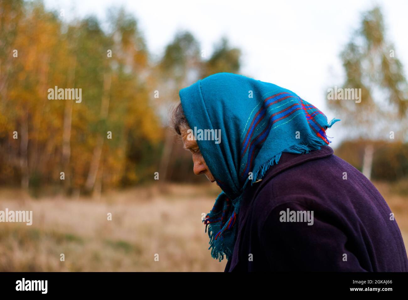 Ritratto defocus della nonna russa anziana in piedi nel parco giallo autunno. Donne anziane in cappotto e scialle. Persona triste. Sfondo della natura. O Foto Stock