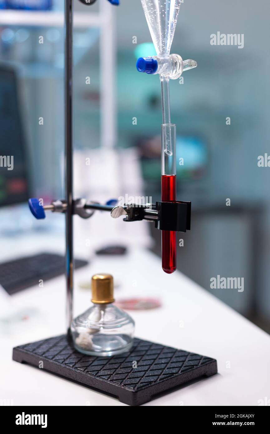 Apparecchiatura per laboratori scientifici e provetta con sangue per lo sviluppo sanitario. Tubo gocciolatore chimico con matraccio in vetro per esami in laboratorio di microbiologia presso la clinica. Strumenti professionali Foto Stock