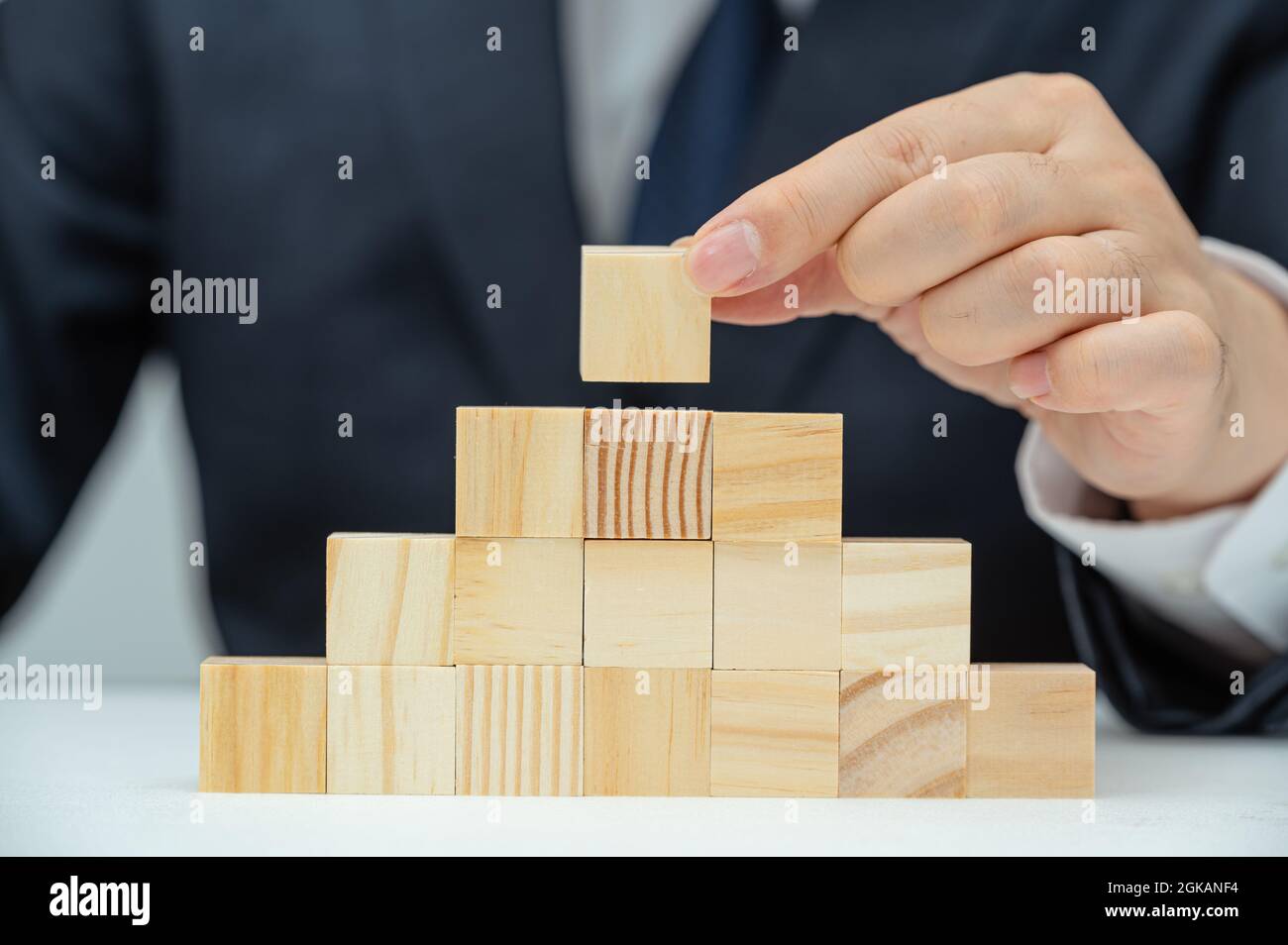 Le mani di un uomo d'affari maschile che sta impilando blocchi di legno. Concetto aziendale. Foto Stock Le mani di un uomo d'affari maschile che sta impilando blocchi di legno. Concetto aziendale. Foto Stock