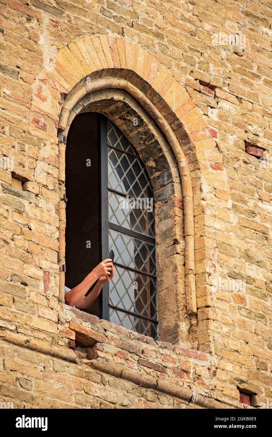 Tourist scatta foto da una finestra del castello medievale di Serralunga d'Alba, Piemonte, il quartiere del vino delle Langhe e patrimonio dell'umanità dell'UNESCO, Italia, verticale Foto Stock