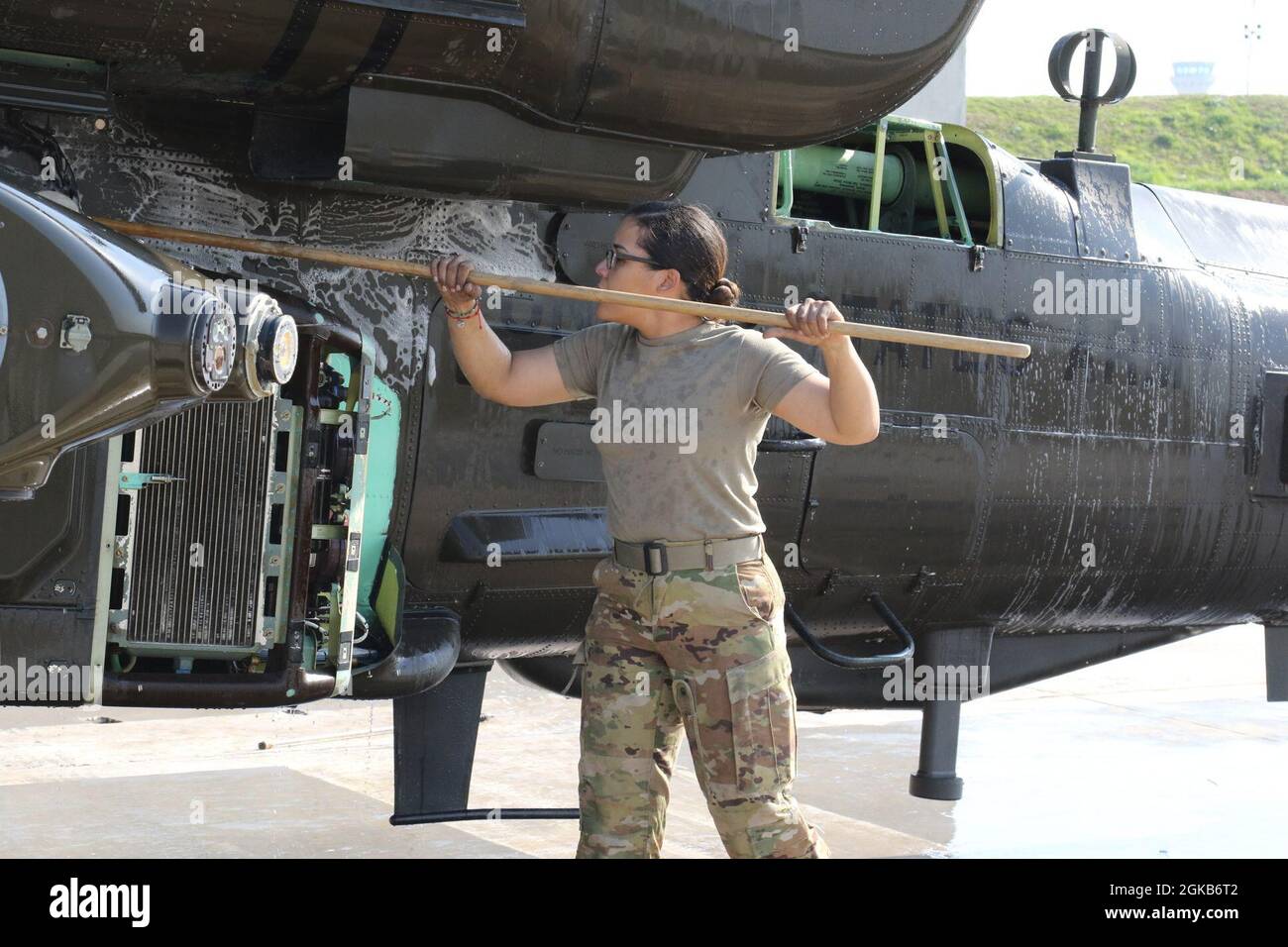 SPC dell'esercito degli Stati Uniti. Thamar Ramos, maintainer presso Alpha Company, 1-82 Battaglione di ricostruzione attacco, 28 brigata aerea di combattimento, pulisce un elicottero AH-64 Apache in un campo aereo nell'area operativa del 28° ECAB in Medio Oriente. Foto Stock