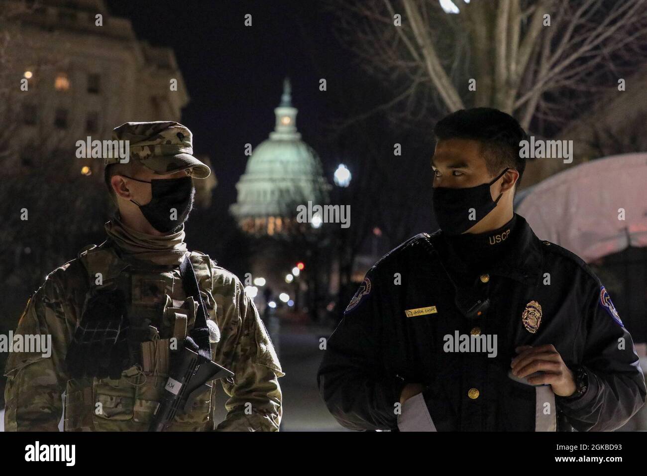 L'ufficiale Jason Caspe, a destra della polizia del Campidoglio degli Stati Uniti, e SPC. Caleb Kink, della 577th Engineer Company, ha una discussione e stare in guardia vicino al Campidoglio degli Stati Uniti a Washington, D.C., 3 marzo 2021. La Guardia Nazionale è stata invitata a continuare a sostenere le forze dell'ordine federali con sicurezza, comunicazioni, evacuazione medica, logistica e supporto per la sicurezza alle agenzie statali, distrettuali e federali fino a metà marzo. Foto Stock