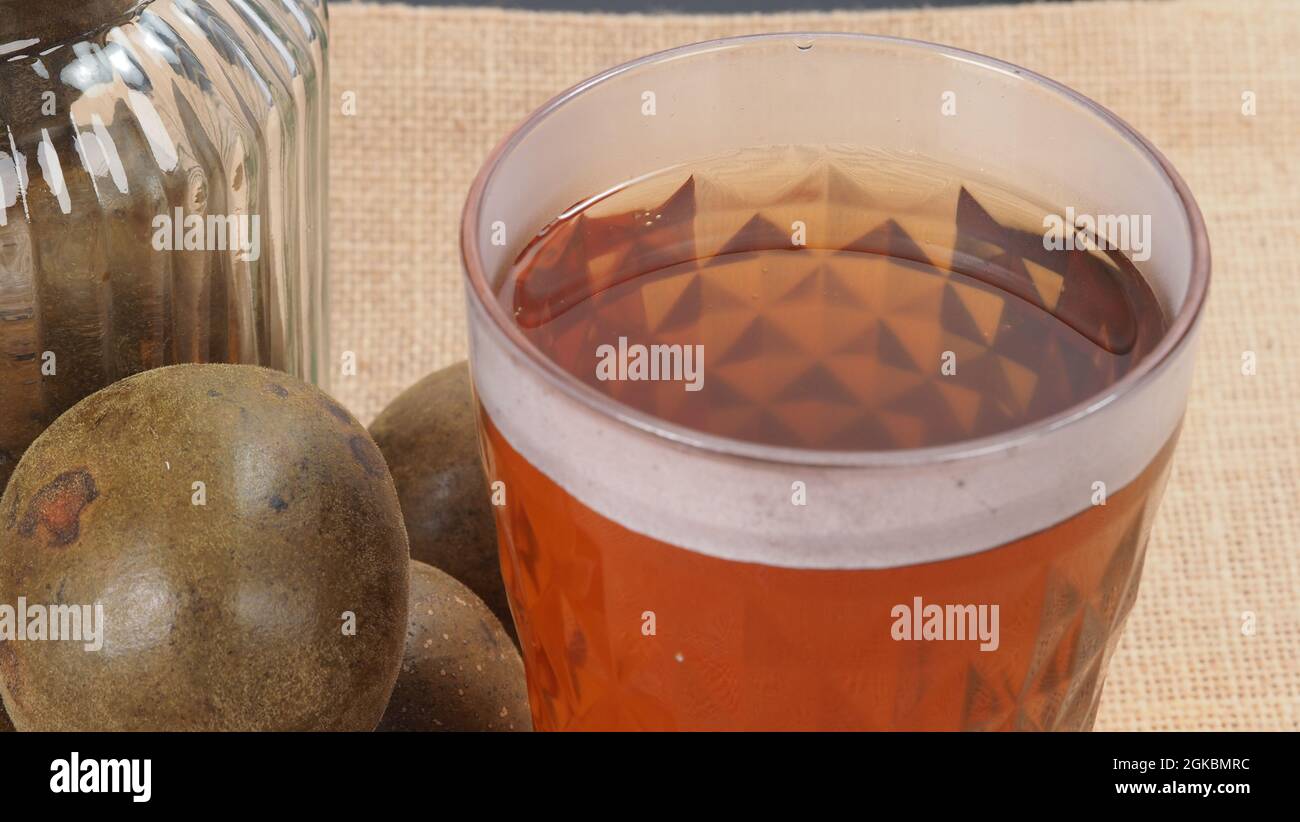 Monk frutta o Luo Han Guo. Frutta secca per una sana bevanda dolcificante. Rimedio naturale alle erbe e sfondo bottiglia di vetro. Mistico bevanda di frutta per chi conce Foto Stock