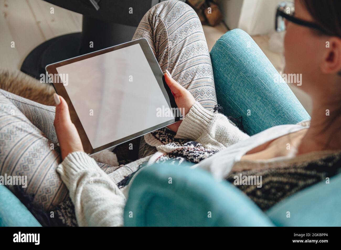 donna seduta in comoda poltrona, con coperta calda, con tablet Foto Stock