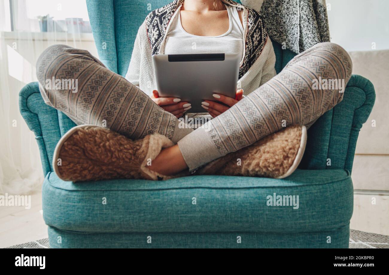donna seduta in comoda poltrona, con coperta calda, con tablet Foto Stock