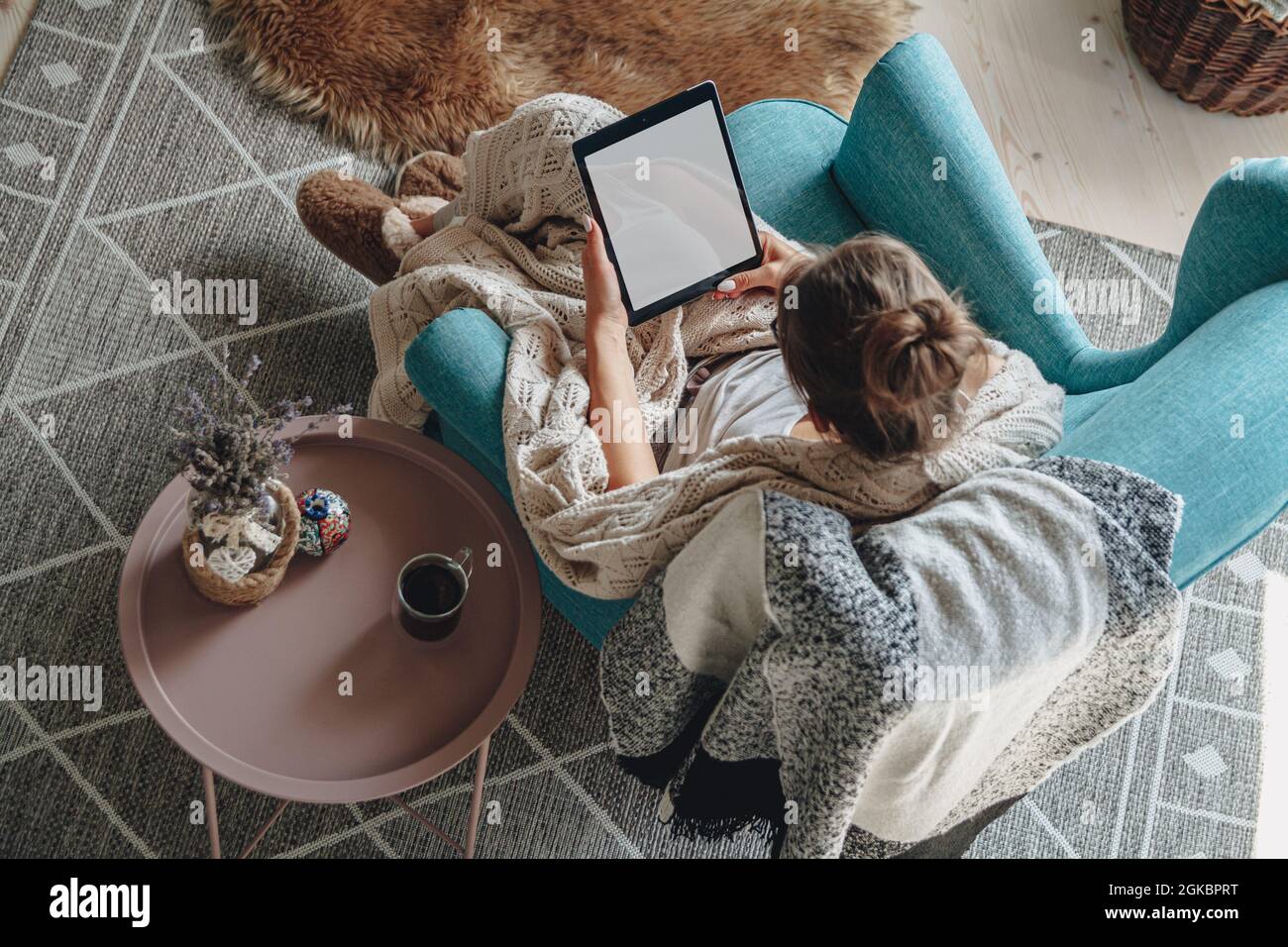 donna seduta in comoda poltrona, con coperta calda, con tablet Foto Stock