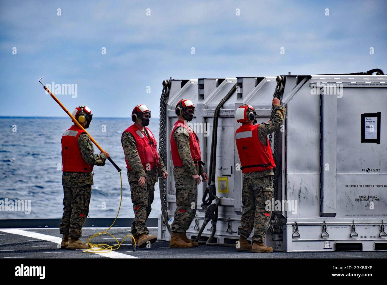 I membri dell’equipaggio di marinai di servizio civile a bordo della nave militare Sealift Command dry cargo/munizioni USNS Richard E. Byrd (T-AKE 4) assistono nelle operazioni in elicottero durante il primo trasferimento in mare della Marina di un simulatore di carico del modulo di potenza del motore F135, 6 marzo, al largo della costa di San Diego. Il modulo è stato trasferito dal ponte di Byrd alla portaerei nucleari USS Carl Vinson (CVN 70) della Marina statunitense di classe Nimitz e di nuovo a Byrd tramite EurocopterAS332 Super Puma e un corpo della Marina statunitense CH-53E Super Stallion elicotteri. Foto Stock