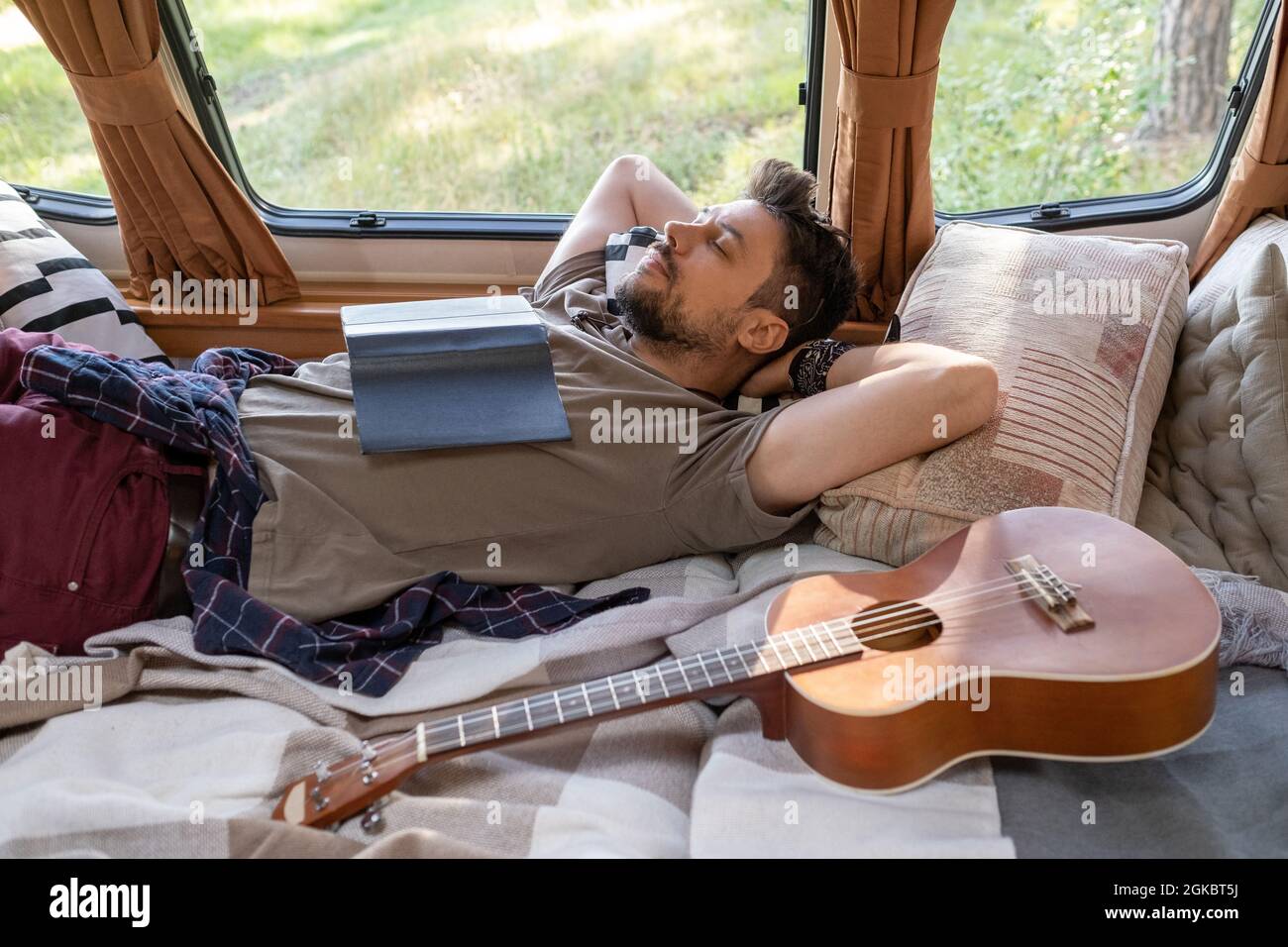 Ragazzo stanco che napping o daydreaming a letto in casa su ruote il giorno d'estate Foto Stock