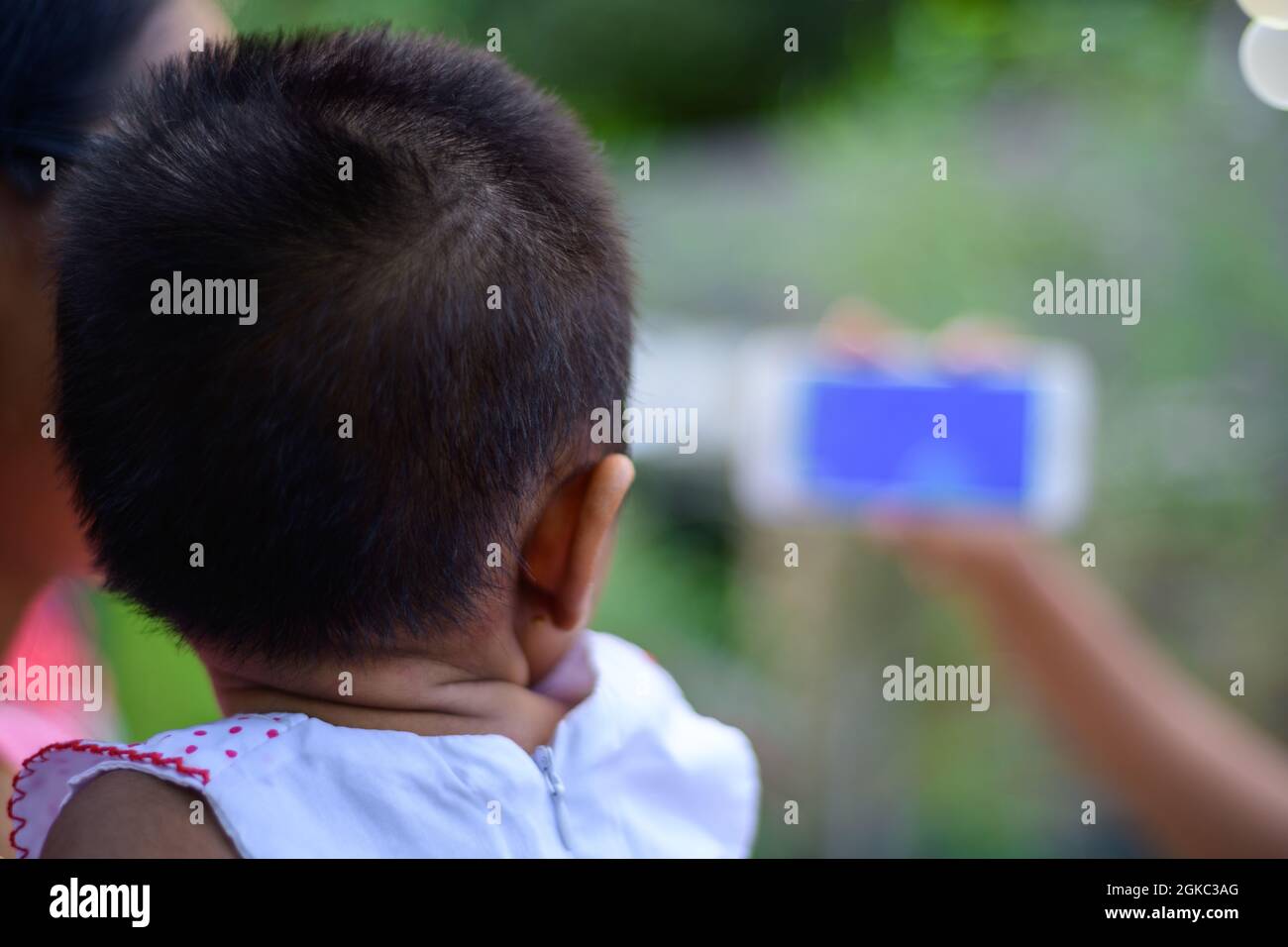 Piccolo bambino che guarda un cartone animato su un telefono cellulare, i genitori che usano i video mobili per fermare i bambini piangere. Il concetto di sviluppare l'apprendimento infantile. Ragazza ho Foto Stock