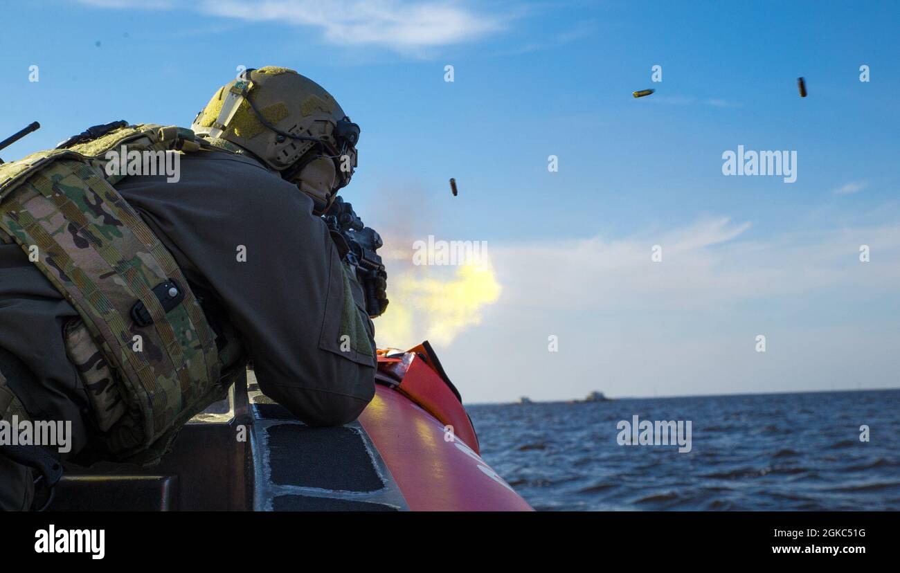 Un guardiano della costa degli Stati Uniti con un team di risposta alla sicurezza marittima (MSRT) spara a bersagli attraverso l'acqua durante l'addestramento avanzato di abilità della pistola della macchina di interdizione della barca vicino al bombardamento di Target 9, Carolina del Nord, 9 marzo 2021. La missione di MSRT è quella di condurre una risposta alle minacce marittime come forza primaria o come parte di un pacchetto della Guardia Costiera degli Stati Uniti o della forza adattativa interagenzia. Marine Corps Air Station Cherry Point, North Carolina, i siti di addestramento, come BT-11 e BT-9, consentono alle forze provenienti da tutto il Dipartimento della Difesa e del Dipartimento della sicurezza interna di venire e condurre in modo ampio Foto Stock