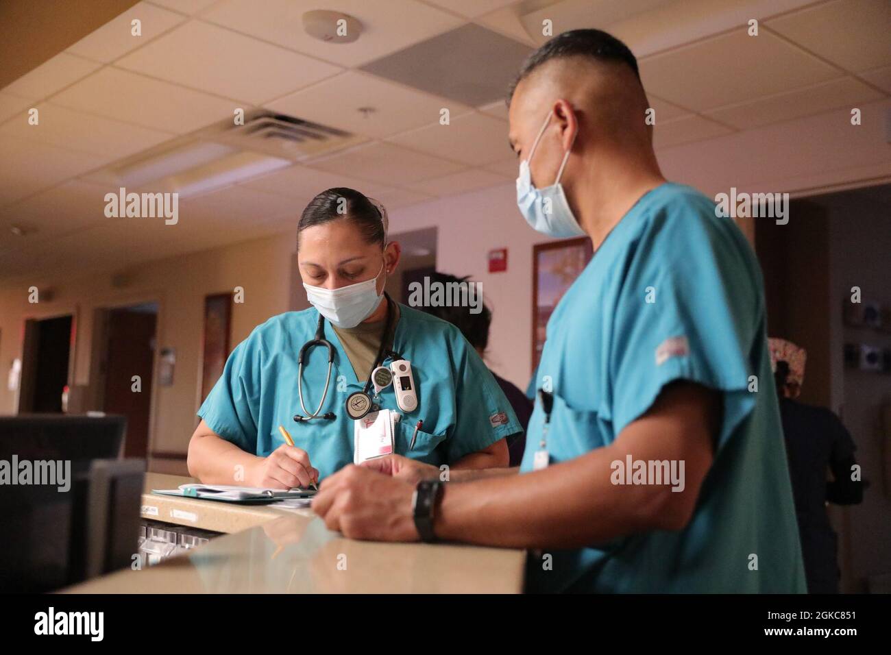 Cruz Williamson (a sinistra) prende appunti dal Capt. Heber Hoil (a destra), entrambi gli infermieri medico-chirurgici, assegnati alla US Army North Task Force 46 durante gli ultimi minuti del loro briefing mattutino sul cambio di turno al Kingman Regional Medical Center, 9 marzo 2021, Kingman, Arizona. Williamson sarà ritenuta responsabile della qualità dell'assistenza ai suoi pazienti per le prossime 12 ore. Il comando del Nord degli Stati Uniti, attraverso l'Esercito del Nord degli Stati Uniti, rimane impegnato a fornire supporto flessibile del Dipartimento della Difesa alla risposta COVID-19 dell'intero governo. Foto Stock