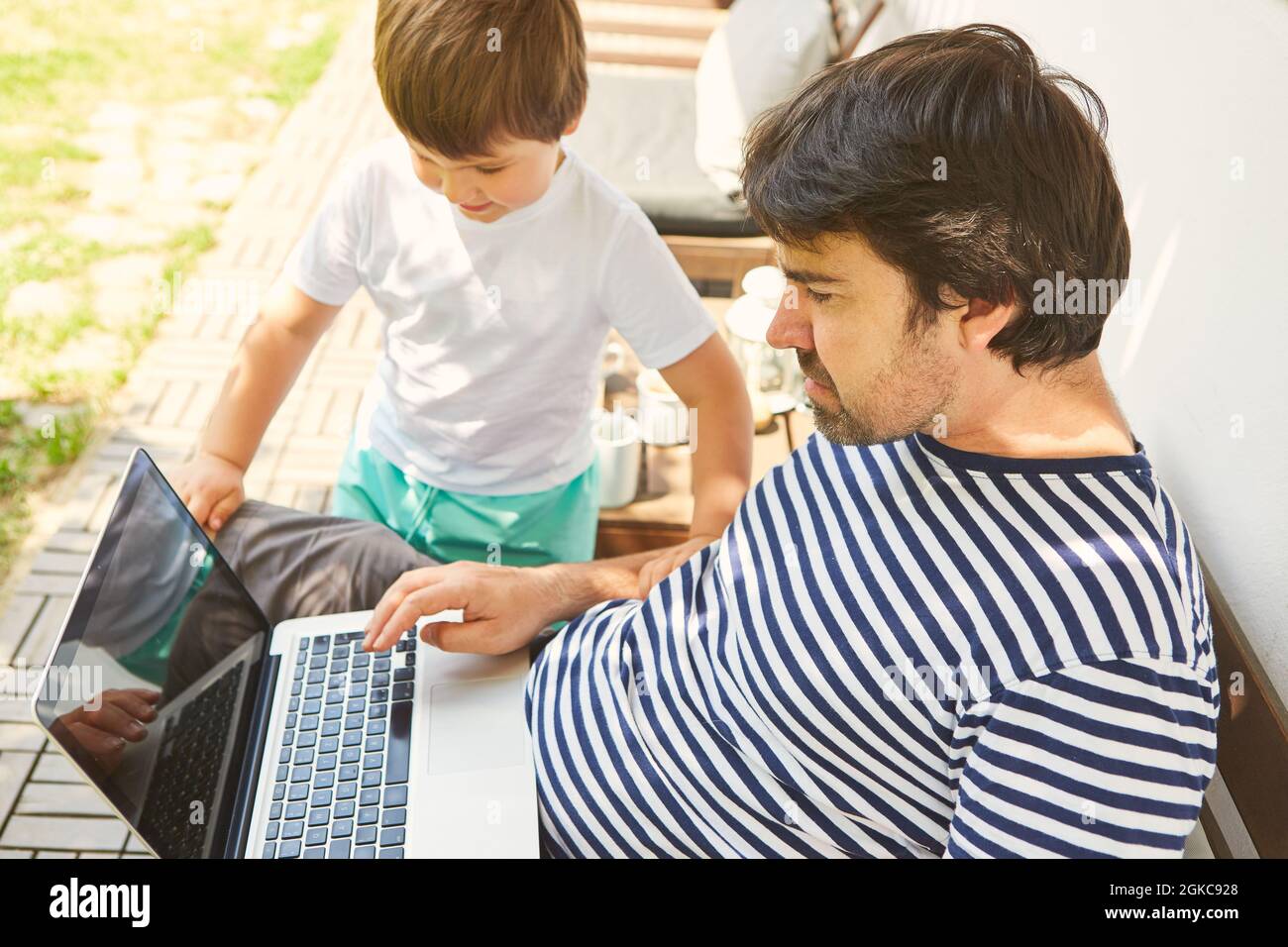 Freelance come padre sul computer portatile insieme a suo figlio a casa Foto Stock