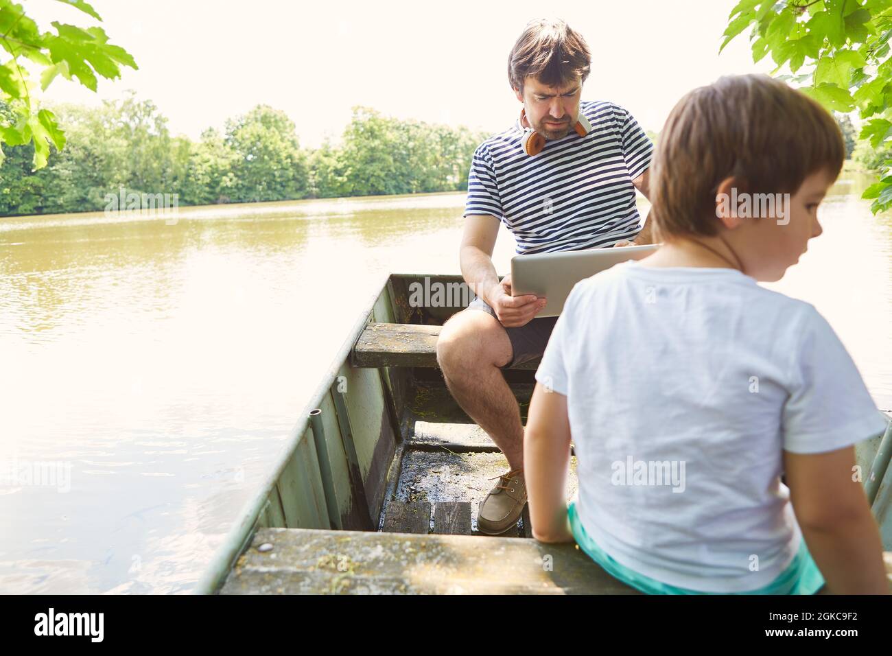 Padre sul PC portatile in viaggio con suo figlio in barca durante le vacanze estive Foto Stock