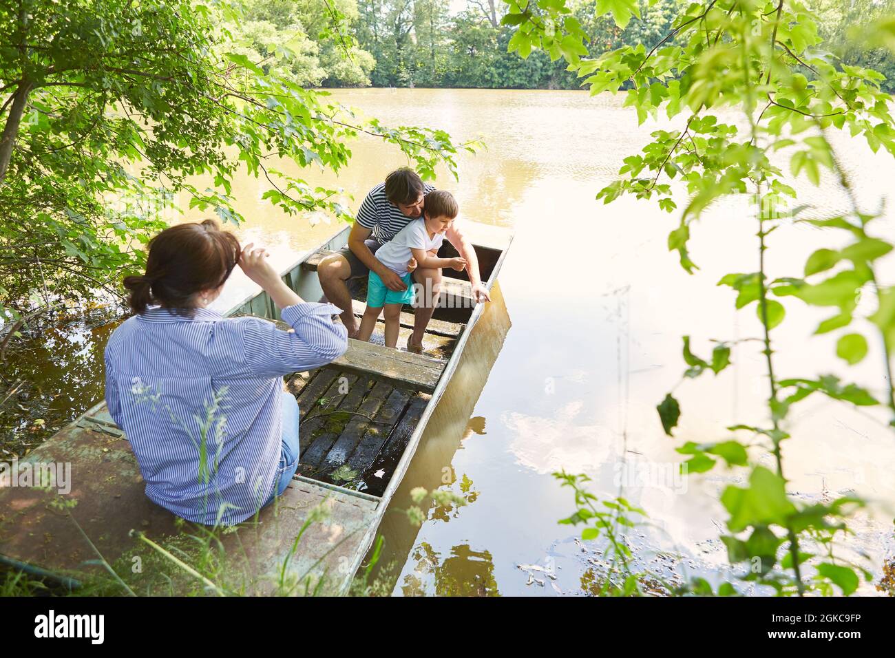Famiglia felice in vacanza estiva con bambino in una barca sul lago in natura Foto Stock