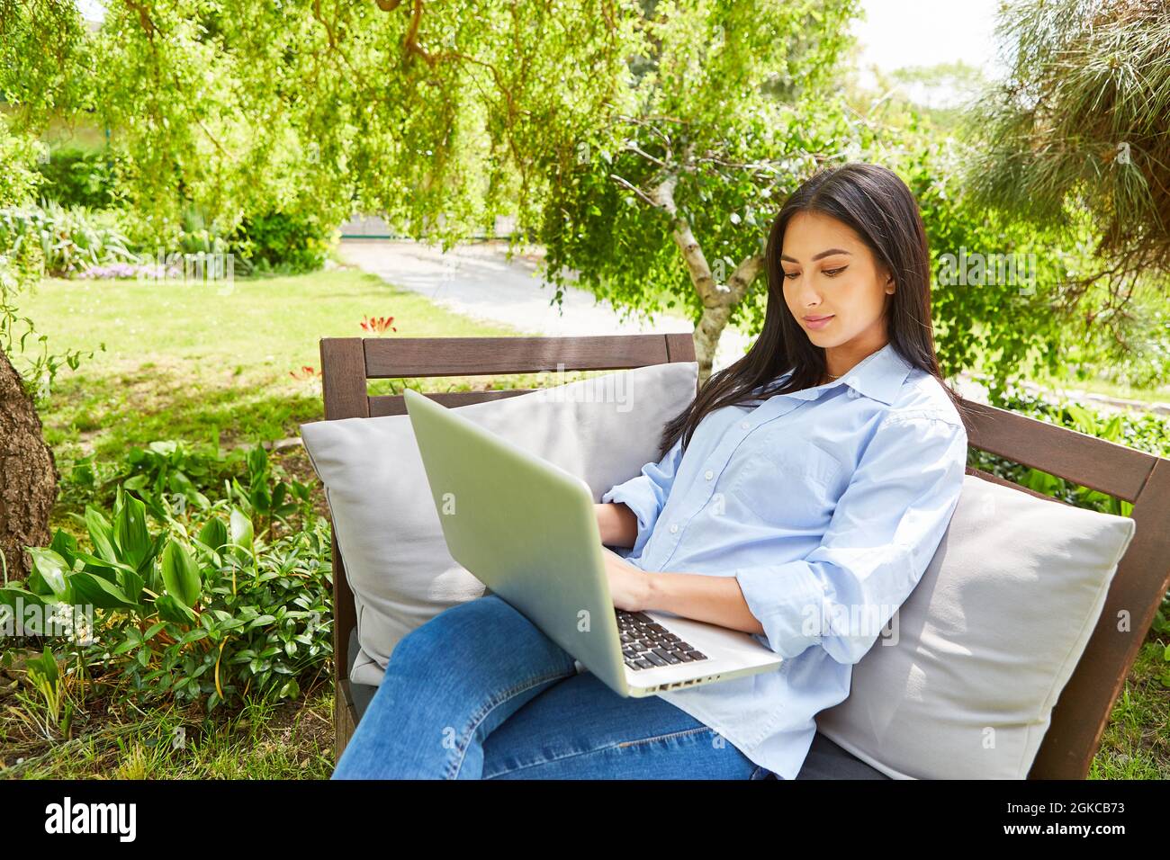 Giovane donna su PC portatile in giardino verde come casa d'ufficio in estate in natura Foto Stock