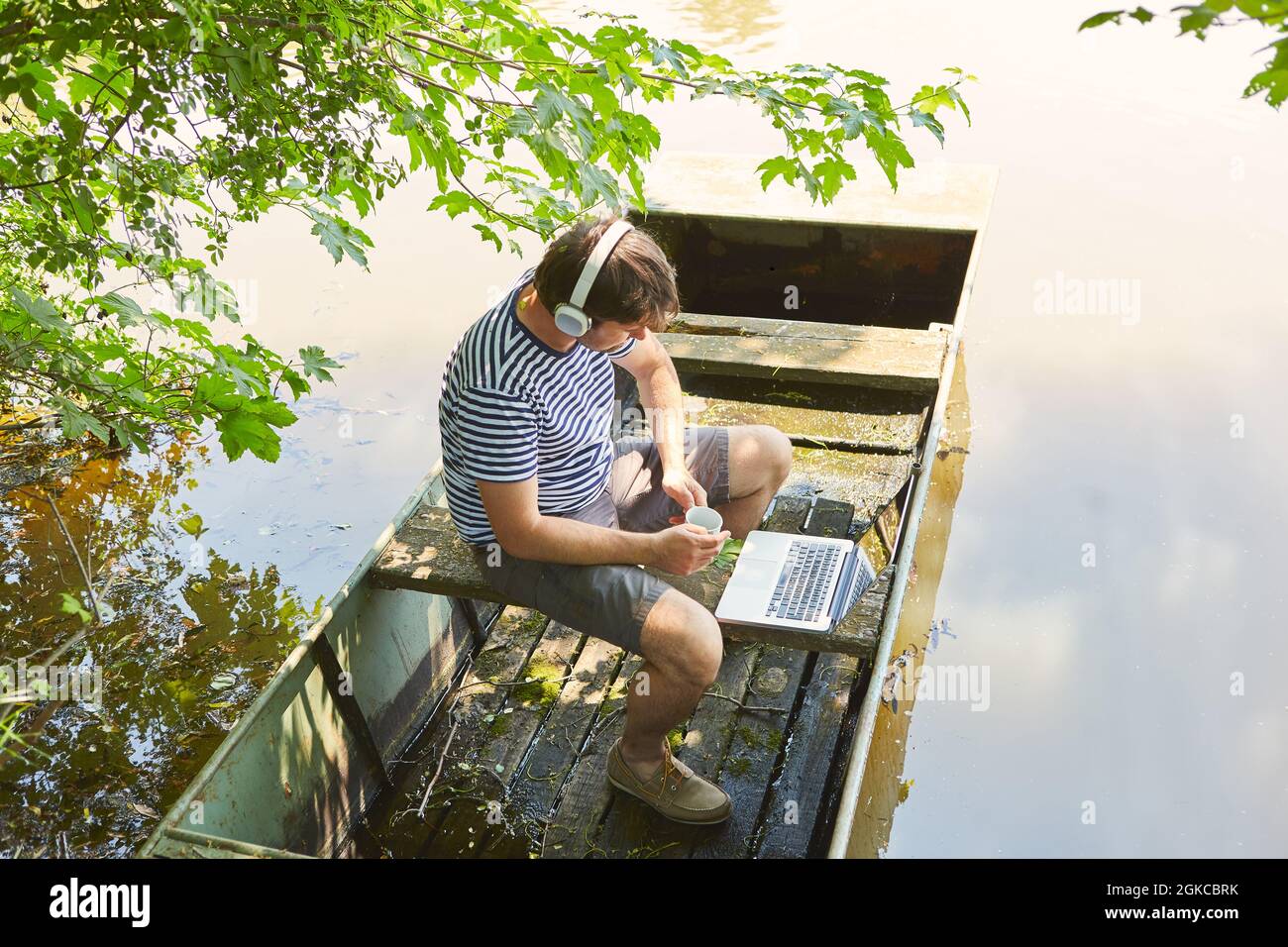 Uomo che lavora su un computer portatile online in vacanza estiva al lago come freelance Foto Stock