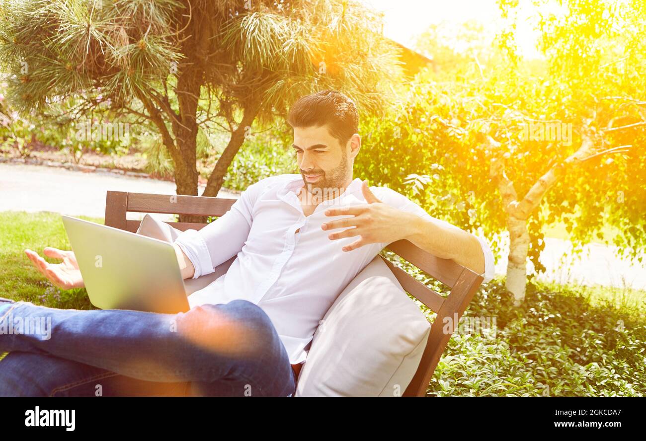 Influencer sui social media di fronte al computer portatile in giardino in estate Foto Stock