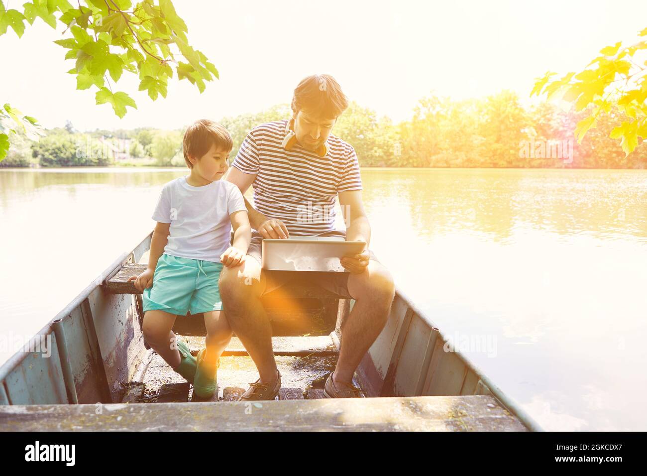 Padre e figlio vanno insieme in barca su un lago in estate Foto Stock