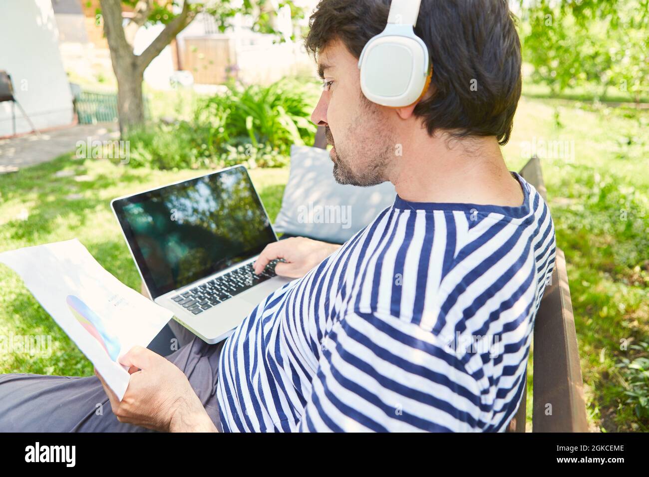 Freelance al computer portatile online durante la pianificazione di un progetto nel giardino verde Foto Stock