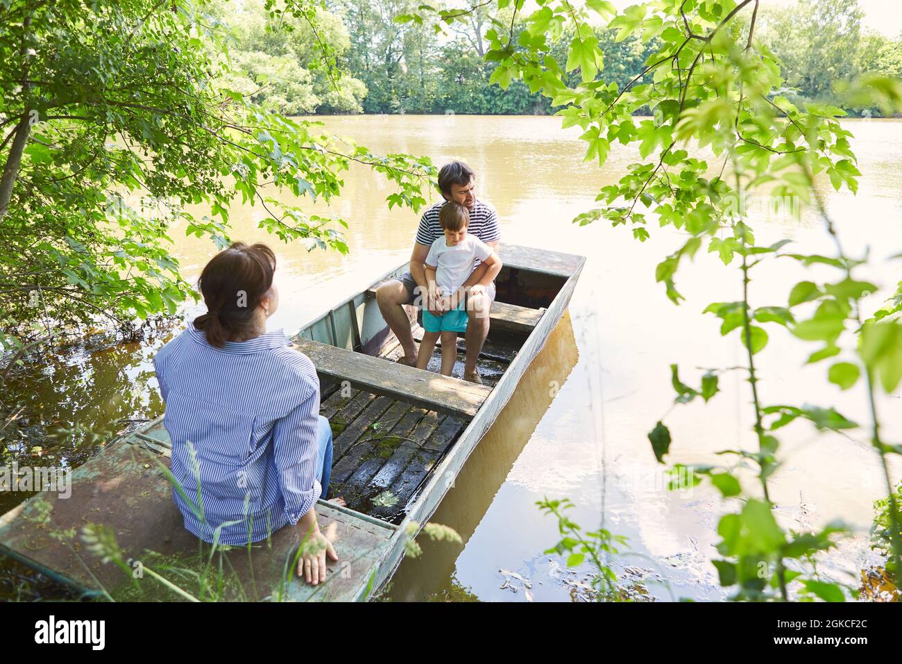Famiglia con bambino in un viaggio nella natura in estate seduto in una barca sul lago Foto Stock