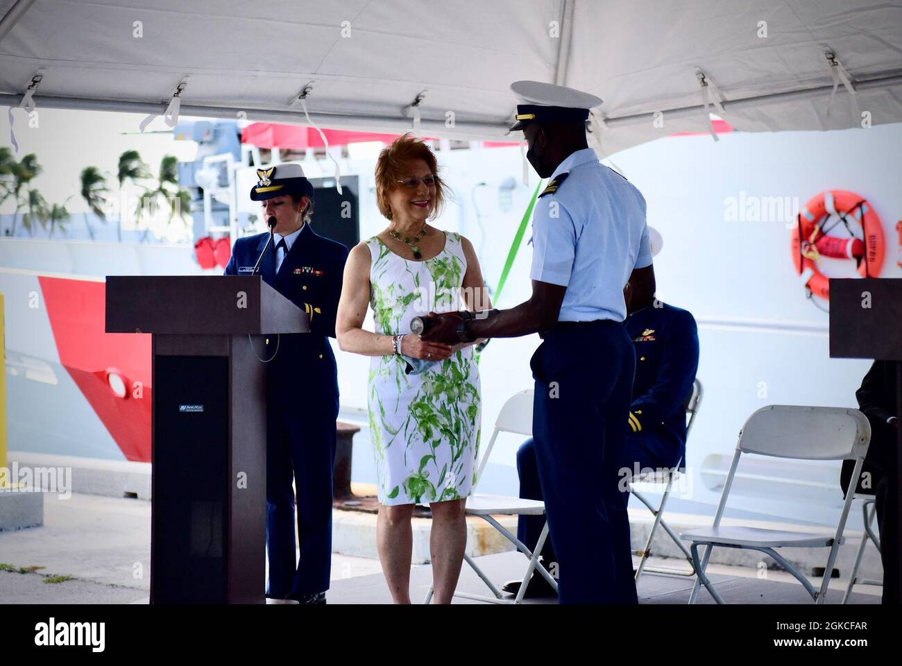 La signora Gail Fresia, una nuora di Robert Goldman, presenta il vetro lungo al Lt. j.g. Nicholas Kambela, nella tradizione nautica, per impostare il primo orologio a bordo della USCGC Robert Goldman (WPC 1142) il 12 marzo 2021, a Key West, Fla. Il Robert Goldman è stato ufficialmente commissionato in servizio e ora transitare in Bahrain per il servizio come parte delle forze di Patrol sud-ovest Asia. Foto Stock