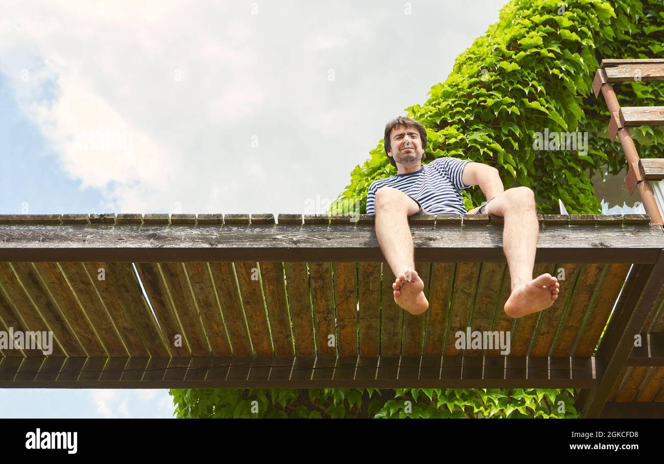 Giovane uomo come freelance seduto su un molo vicino al lago in estate in vacanza Foto Stock