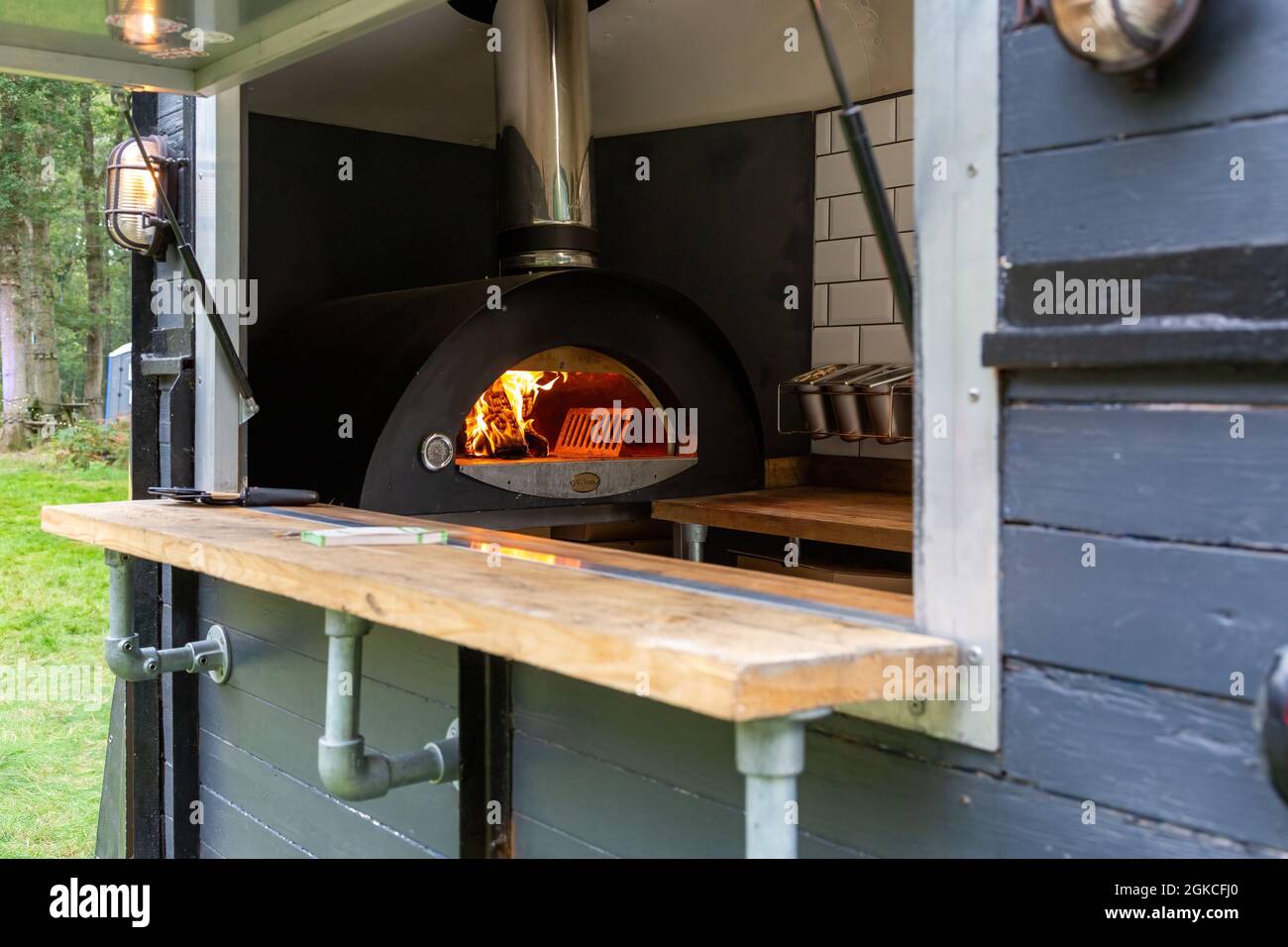 guardando attraverso un portello di un furgone mobile di ristorazione con un forno della pizza che brucia all'interno Foto Stock