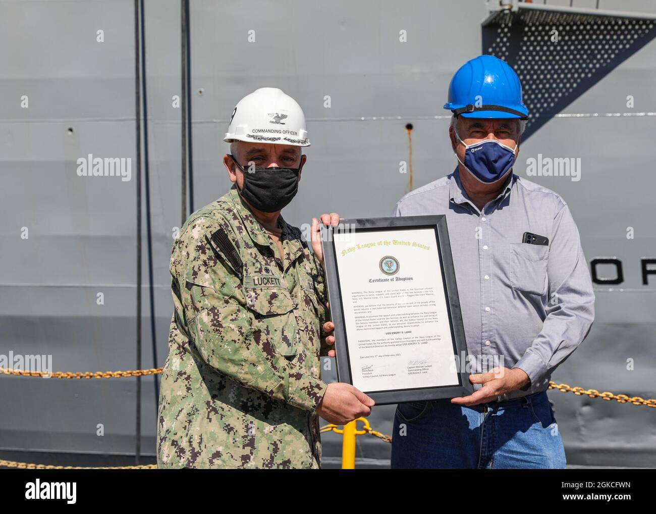 VALLEJO, California (12 marzo 2021) Steve Nash, presidente del consiglio per la Lega Navale del Consiglio Vallejo degli Stati Uniti, presenta al Capitano Michael Luckett, comandante della gara sottomarina USS Emory S. Land (AS 39), un certificato di adozione durante la cerimonia di adozione della nave a Mare Island Dry Dock, Marzo 12. La Navy League è un'organizzazione civile senza scopo di lucro fondata nel 1902 con il sostegno del presidente Theodore Roosevelt. Foto Stock