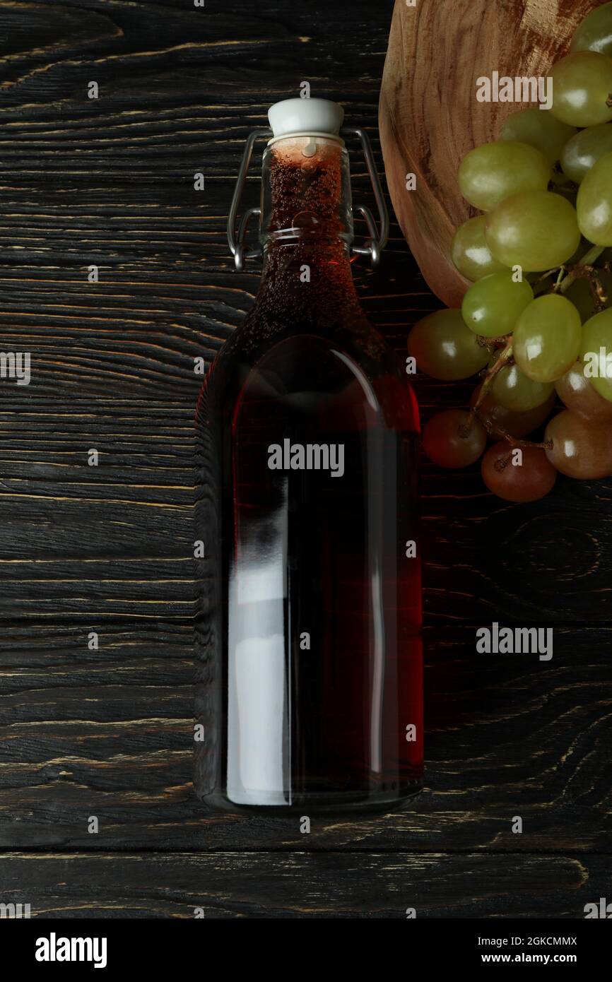 Bottiglia di aceto e uva su tavola rustica in legno Foto Stock