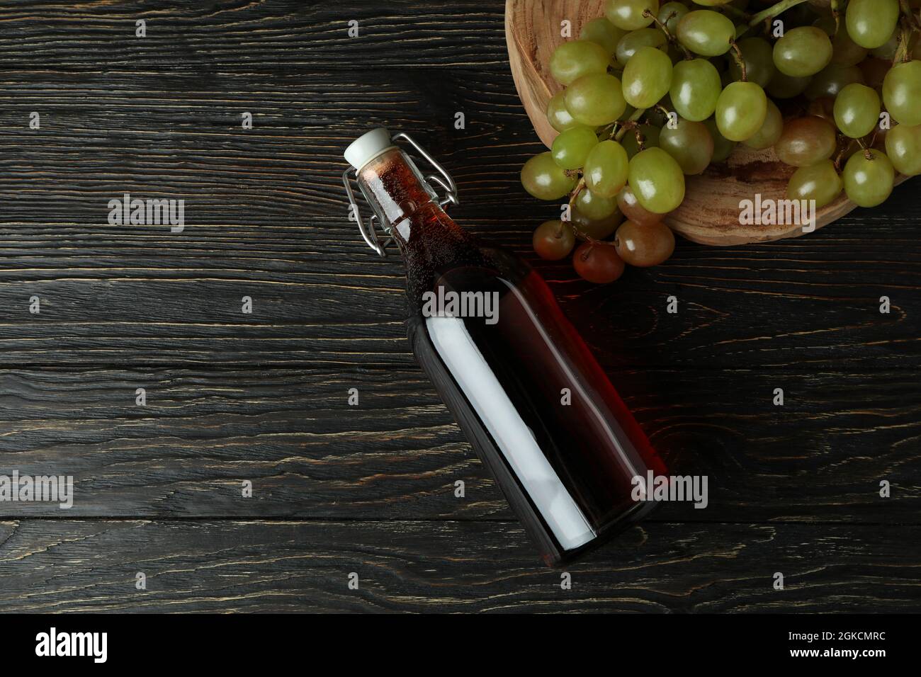 Bottiglia di aceto e uva su tavola rustica in legno Foto Stock