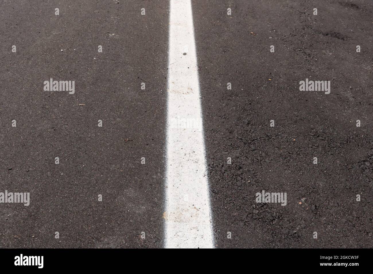 Asfalto appena realizzato con un po' di sporco e la sua consistenza, con una striscia bianca dipinta al centro dell'immagine Foto Stock