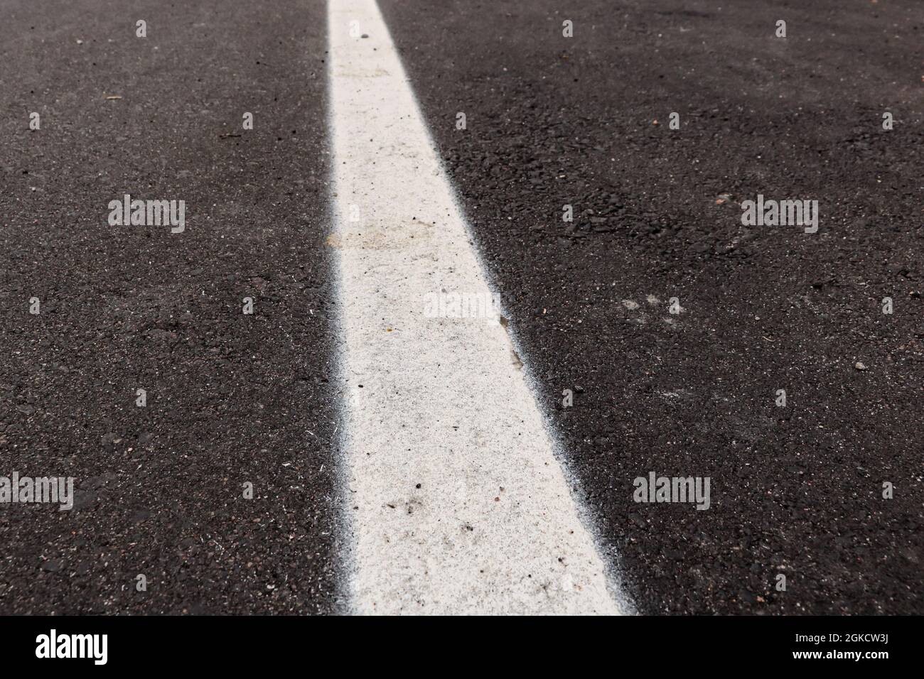 Asfalto appena realizzato con un po' di sporco e la sua consistenza, con una striscia bianca dipinta al centro dell'immagine Foto Stock