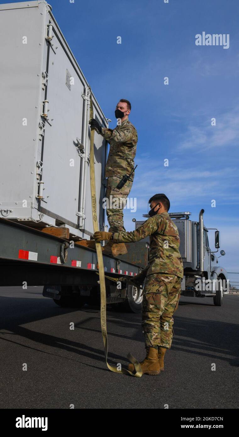 Airmen dal 92nd Logistics Readiness Squadron cinghia di carico ad un semi-rimorchio per il trasporto sulla base aerea di Fairchild, Washington, 18 marzo 2021. Il set di missioni di Fairchild AFB va oltre il rifornimento di aria, le spedizioni di carichi e l’evacuazione aeromedica sono altri attori chiave della missione. Foto Stock