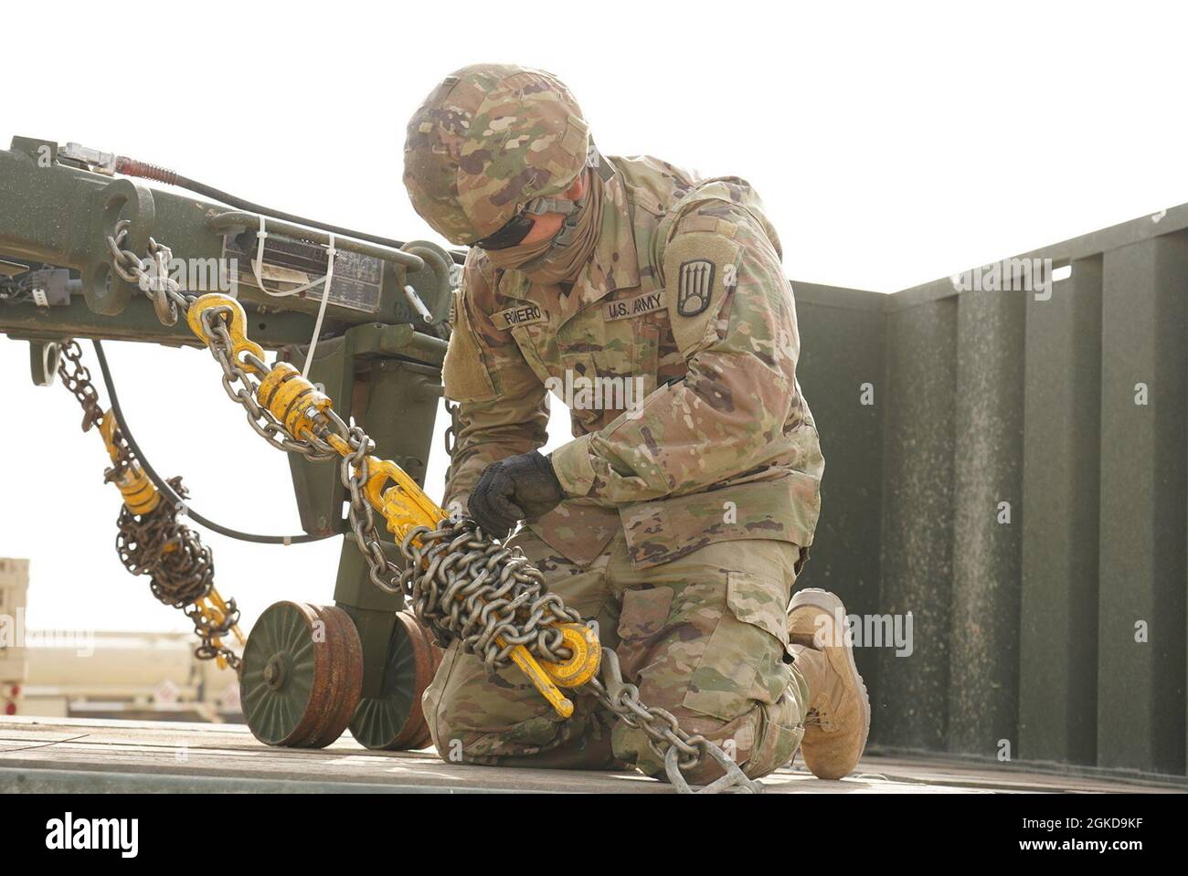 Guardia Nazionale del New Mexico SPC. Jordan Romero, schierato come operatore di trasporto a motore con la Las Vegas, N.M., con sede a 720th Transportation Company, 1st Platoon, 1st Squad to Camp Arifjan, Kuwait. Romero avvolge e fissa la catena in eccesso ai raccoglitori a catena come fasi finali di fissare il suo carico al suo rimorchio prima di lasciare il Porto di Shuaiba, Kuwait. Foto Stock