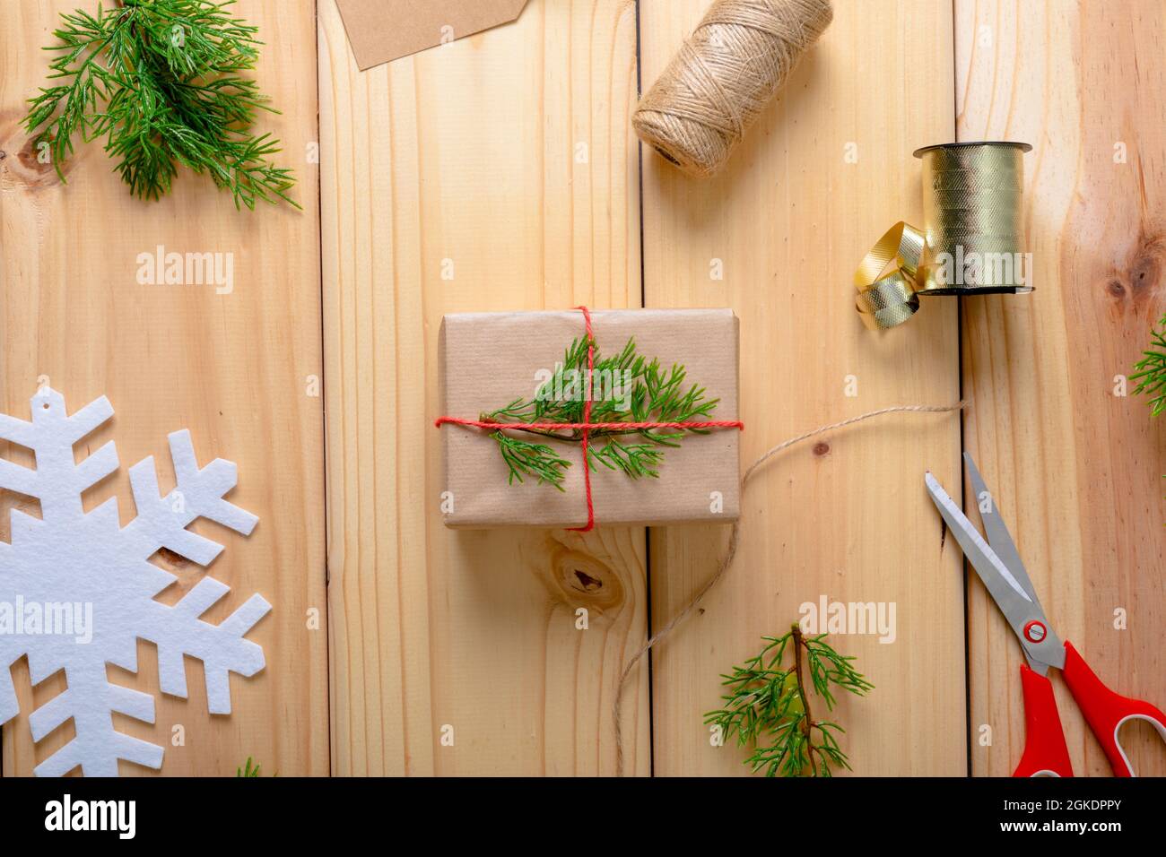 Composizione di decorazioni natalizie con regalo, nastro e forbici su sfondo in legno Foto Stock