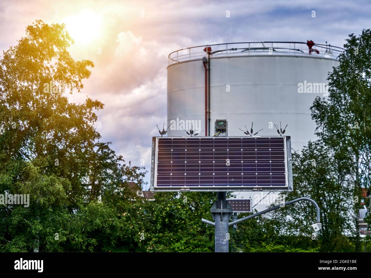 Grande serbatoio dell'olio e piccoli collettori per ottenere energia dal sole che brilla dal cielo Foto Stock