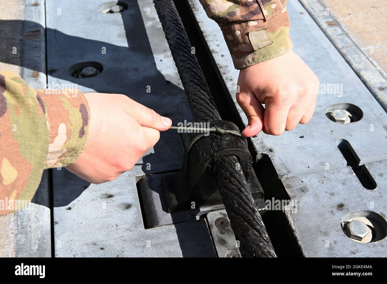 US Air Force Senior Airman Derek Sjogren, 173esimo tecnico di produzione di energia elettrica Squadron ingegneria civile, fissa il cavo ai blocchi di supporto in gomma sul kit di arresto barriera -12 a Kingsley Field a Klamath Falls, Ore., 25 marzo 2021. Il CES 173 è responsabile della manutenzione di tutte le parti del BAK-12, che consente di arrestare un'aquila F-15 disabilitata durante un atterraggio sulla pista. Foto Stock