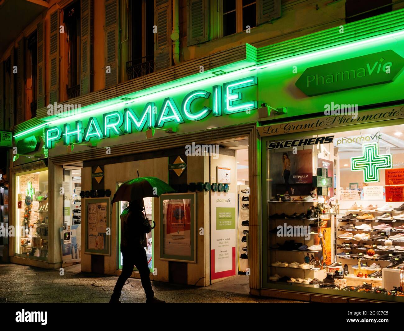 Uomo singolo con ombrello di fronte al negozio di droga farmacia Foto Stock