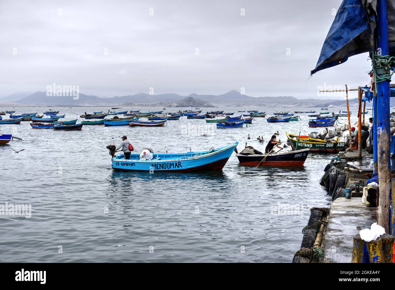 El Dorado, Perù - 30 luglio 2021: Uomini che operano piccole barche da pesca con piccole barche da pesca ormeggiate, spiaggia e montagne sullo sfondo Foto Stock