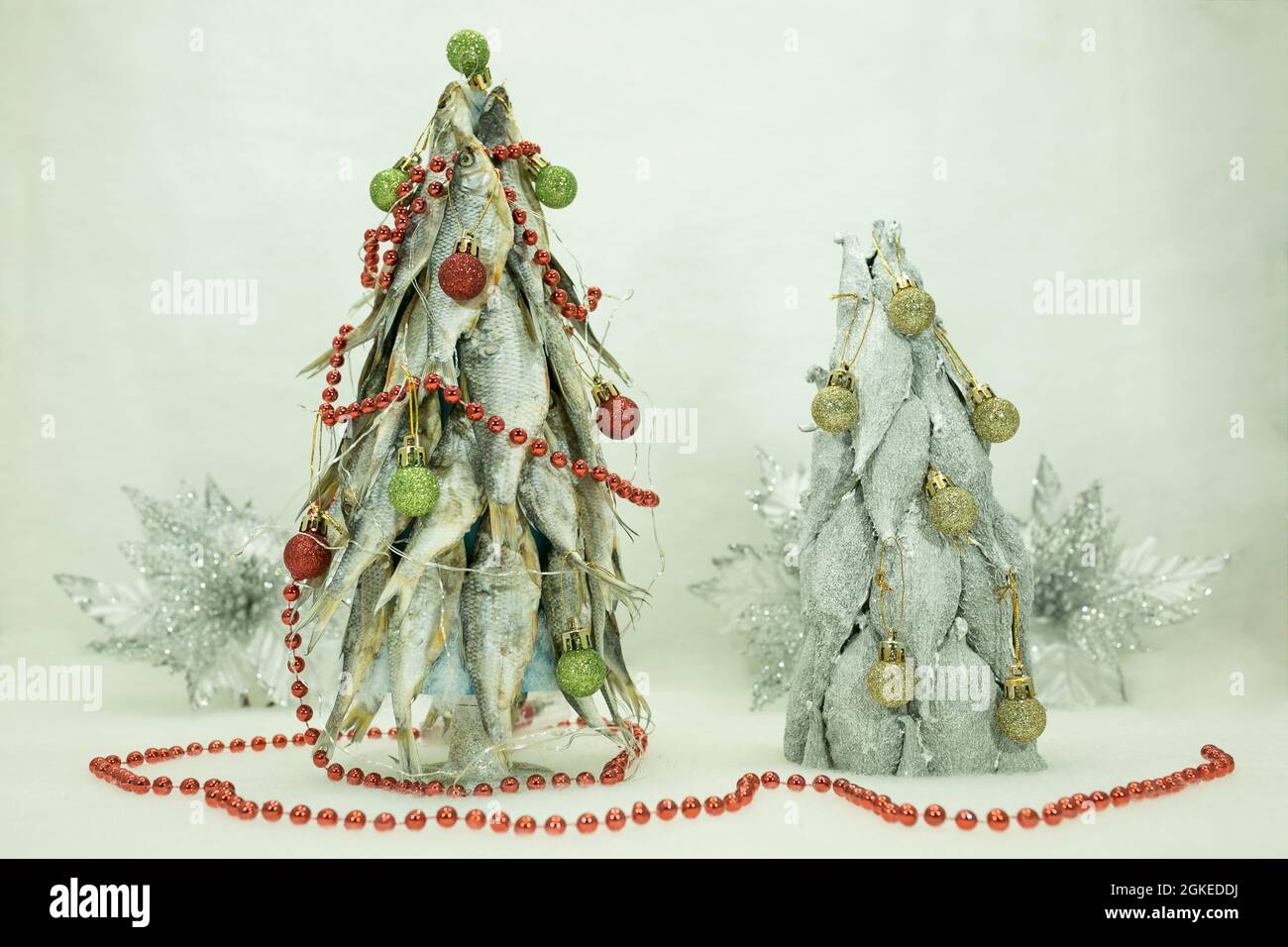 Due alberi di Natale. Gli alberi di Natale sono fatti di pesce essiccato.  Anno nuovo per il pescatore. Lo sfondo è decorato con fiori d'argento-neve  di Natale Foto stock - Alamy