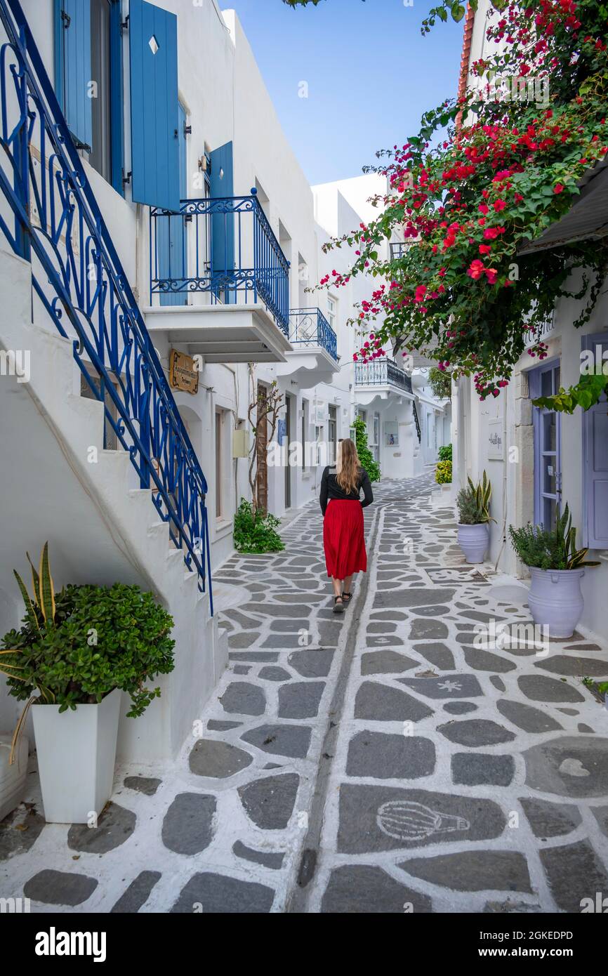 Giovane donna con abito che cammina attraverso il vicolo con le case delle Cicladi, la città vecchia di Parikia, Paros, Cicladi, Grecia Foto Stock
