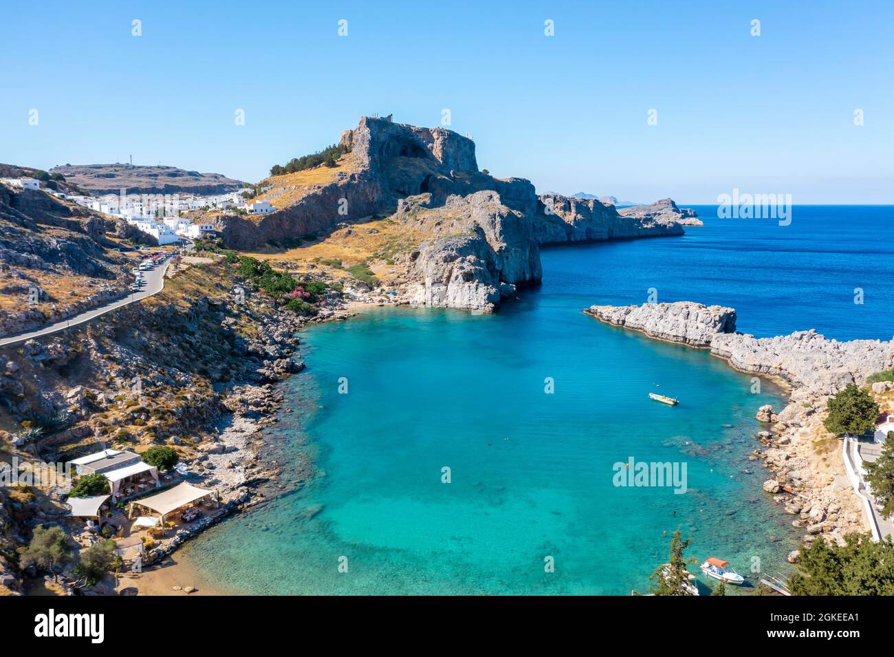 Mare turchese e spiaggia sabbiosa, Acropoli di Lindos, antica cittadella su una scogliera ripida, Lindos, Rodi, Dodecaneso, Grecia Foto Stock