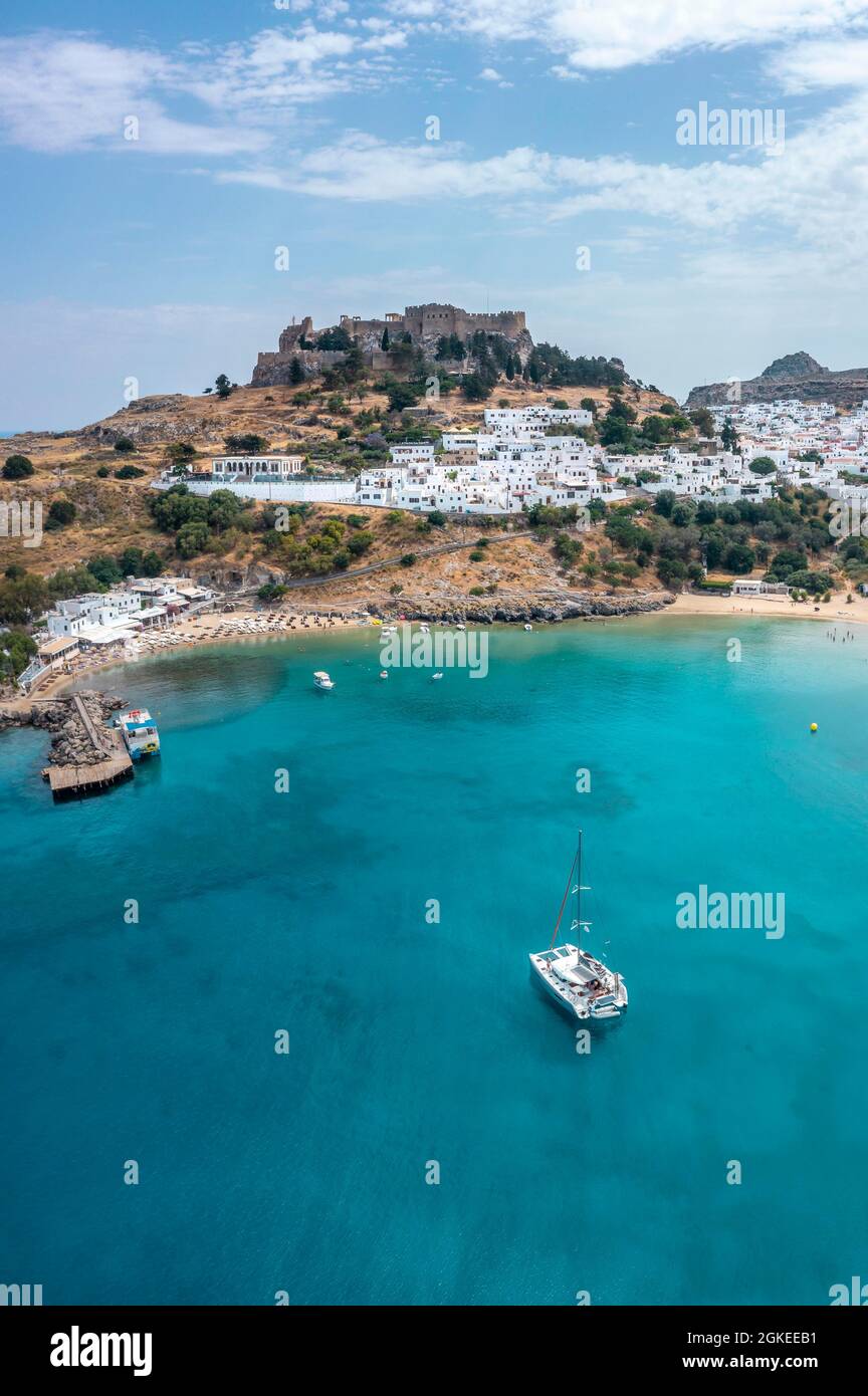 Barca a vela sul mare turchese, spiaggia sabbiosa, acropoli di Lindos, antica cittadella su una scogliera ripida, Lindos, Rodi, Dodecaneso, Grecia Foto Stock