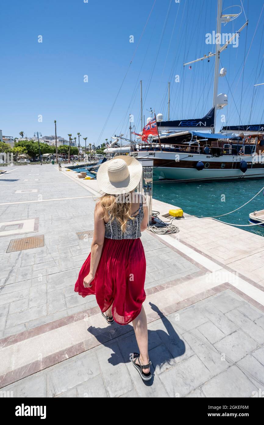 Giovane donna con abito a piedi al porto di Kos, Dodecaneso, Grecia Foto Stock