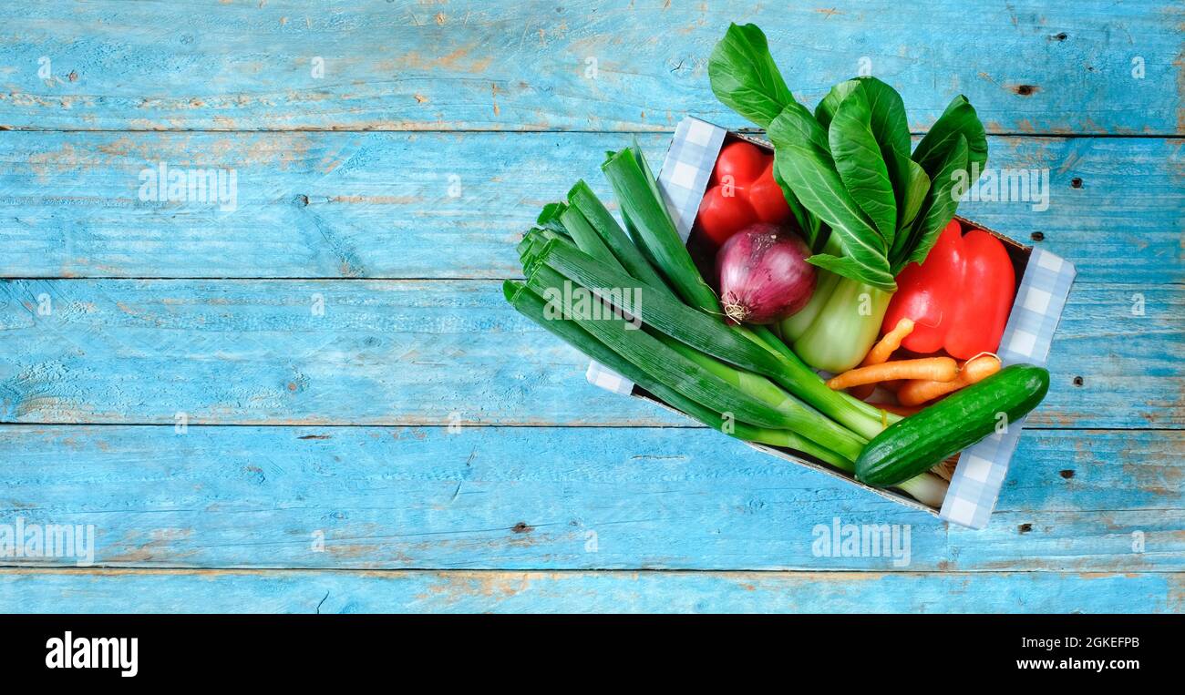 scatola con varie verdure, cibo sano, concetto di dieta, piatto adagiare su tavolo di legno blu Foto Stock