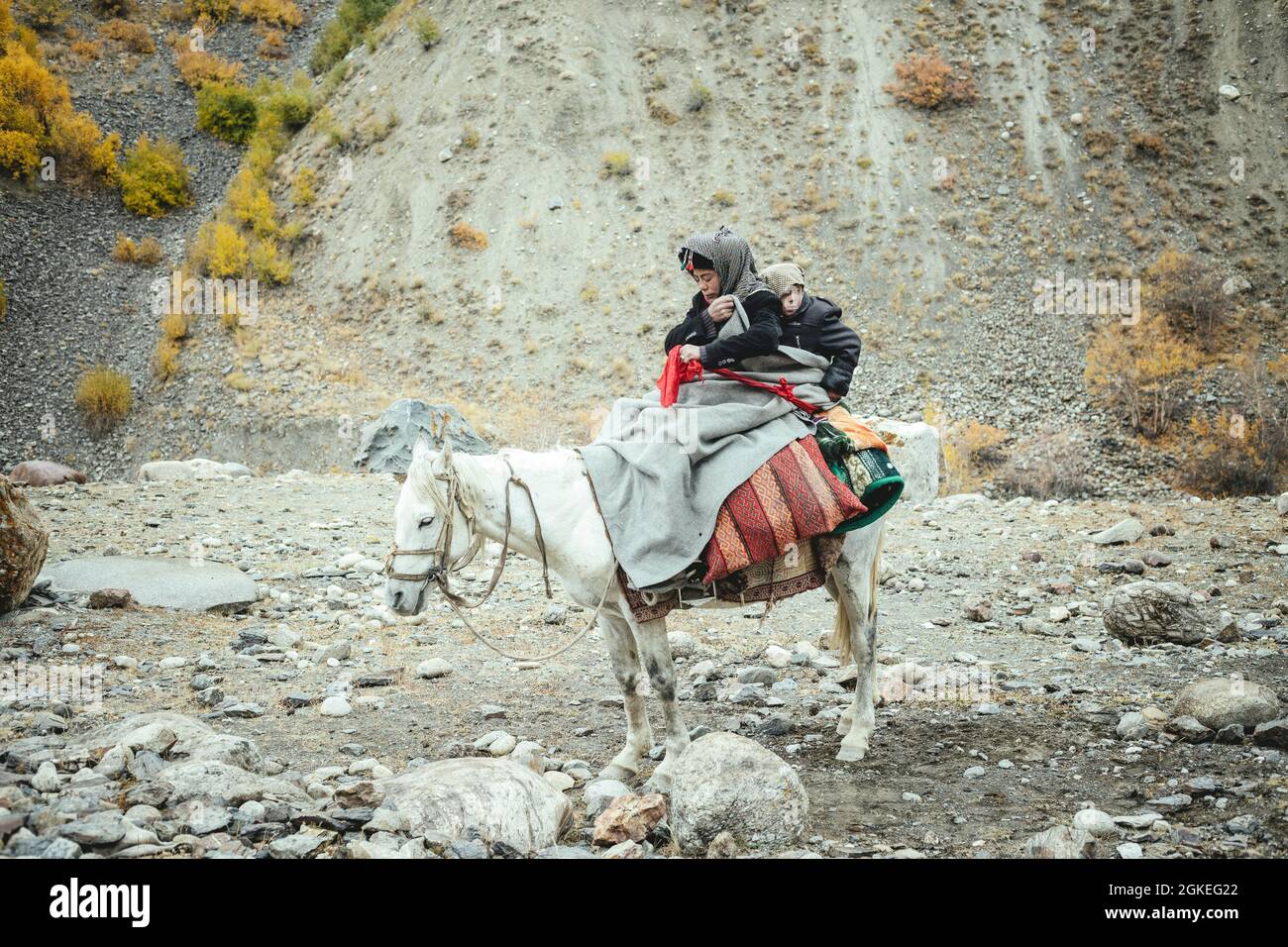 Un ragazzo con il suo fratellino su un cavallo bianco, nomadi Kirghizistan, Corridoio di Wakhan, Badakhshan, Afghanistan Foto Stock